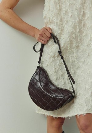Brown, textured leather handbag with a semi-circular shape. Features a zip closure and an adjustable strap with silver hardware.