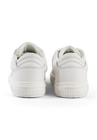 Sneaker bianchi in pelle con finitura liscia, tallone imbottito e dettagli testurizzati. Suola in gomma con scanalature orizzontali per una migliore aderenza.