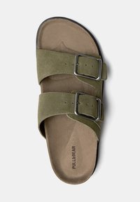 Slidesandal med olivengrønne ruskindsremme, dobbelte metalspænder og en tan farvet polstret indersole. Sort gummi ydersål for holdbarhed.