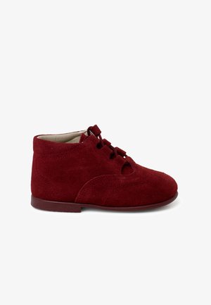 Bottes de cheville en suede rouge avec un bout arrondi, un design à lacets et des détails découpés. Comprend une semelle plate et une surface teksturée.