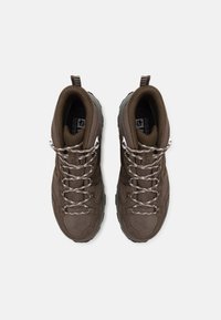 Scarpe da hiking marroni con tomaia in rete e suede, suole in gomma spesse, punte rinforzate e occhielli in metallo, dotate di lacci grigi.