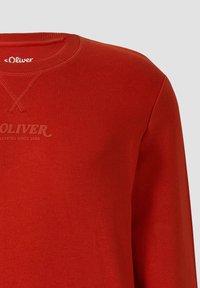 Czerwony długi rękaw bluzy z ribbed crew neck, dekoracyjnymi przeszyciami oraz wytłoczonym logo "s.Oliver Elevated Since 1969" na piersi.