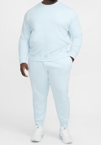Felpa azzurro chiaro e pantaloni abbinati in morbido tessuto, con polsini a costine, collo a girocollo e un piccolo dettaglio con logo.