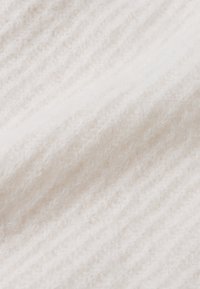 Weißer gestrickter Stoff mit einer weichen, flauschigen Textur und dezenten horizontalen Rippmustern. Das Gesamtbild wirkt leicht und luftig.