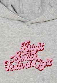 Grau Hoodie mit besticktem Text "Bright Smiles Festival Light" in Pink mit strukturierter Oberfläche, akzentuiert durch kleine goldene Sterne.