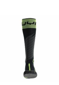 Calcetín hasta la rodilla en negro con detalles verdes, que presenta un diseño texturizado y líneas curvas. Punta reforzada y puño con patrón para un mejor agarre.