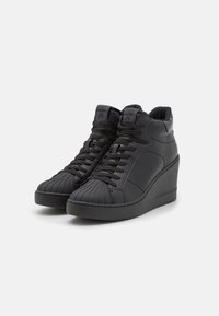 Black wedge sneakers with a textured toe cap, padded collar, and lace-up design. Made of smooth synthetic material with minimal branding.