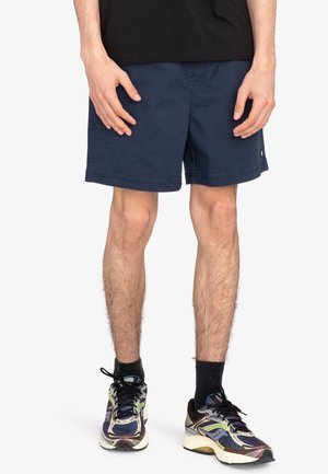 Marineblå shorts med en afslappet pasform, lavet af bomuld, med en flad talje og sidelommer. Stylet med multicolore løbesko.
