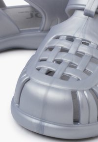 Gray plastic sandal with a woven design on the upper, open sides, and a textured footbed. Smooth finish and rounded toe cap.