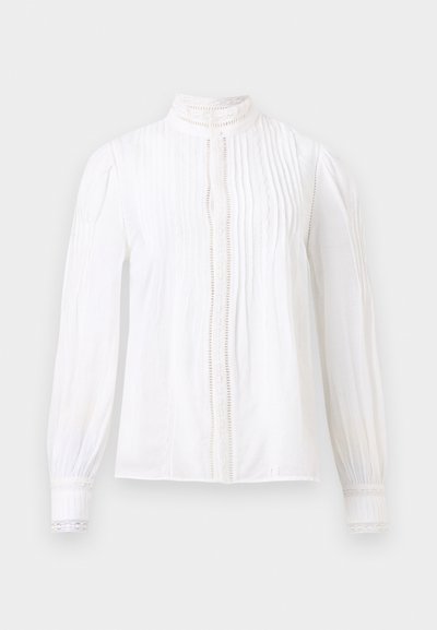 Άσπρο μπλουζάκι με μακριά μανίκια, με πιέτες, δαντελωτό τελείωμα στα μανίκια και στο μπροστινό μέρος, και ψηλό γιακά με λεπτές δαντελωτές λεπτομέρειες.