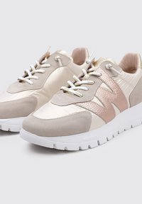 Zapatillas de color claro con un diseño de materiales mixtos de satén y ante, con un acento en oro rosado y suela de goma blanca. Los cordones son metálicos.
