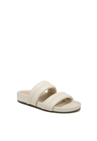 Light beige slide sandals featuring three wide straps, smooth leather material, flat sole, and a minimalist design.