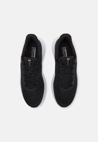 Baskets de sport noires avec une tige en maille, fermeture à lacets et semelle blanche rembourrée. Présente un motif texturé sur la tige pour une meilleure respirabilité.