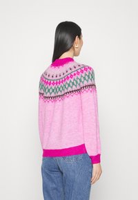 Roosa sviiter, millel on Fair Isle muster rohelises, tumepunas ja pruunis värvitoonis krae ümber. Varrukaotsad ja alläär on erkroosa soonikkoes.