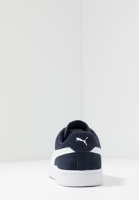 Navy blue suede sneaker with white accents and a padded collar. Features a rubber sole and a logo on the heel. Simple, low-profile design.