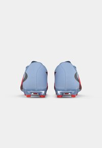 Scarpe da calcio blu con accenti neri e rossi, dotate di un upper testurizzato, design low-profile e tacchetti rossi trasparenti per una migliore trazione.