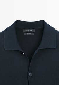 Dunkelblaues Poloshirt aus Baumwolle mit strukturierter Stoffoberfläche, ausgestattet mit Knopfverschluss und klassischem Kragen. Das Etikett trägt die Aufschrift "Massimo Dutti."