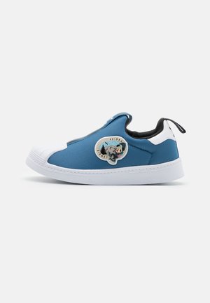 Baskets slip-on bleues avec semelle et embout blancs, intérieur noir, et un patch Adidas Disney montagne et Mickey Mouse sur le côté.