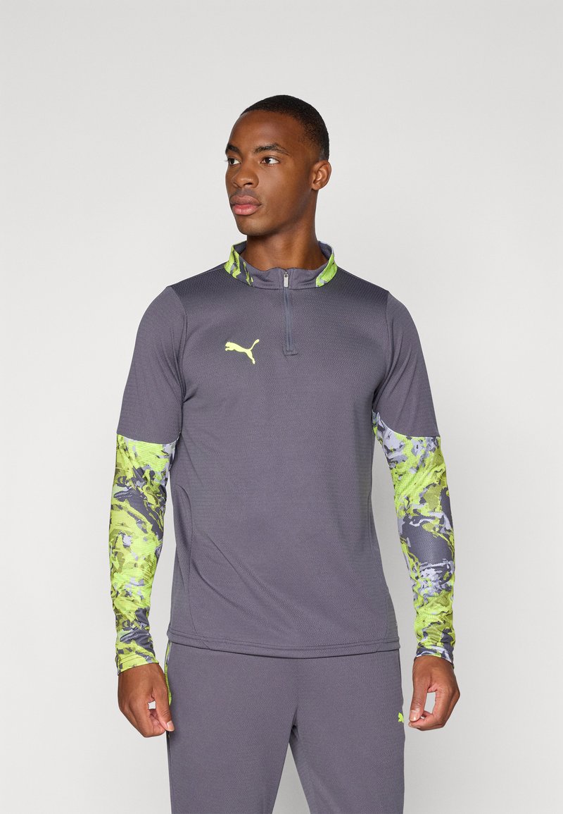 Gray long-sleeve shirt with a quarter zip, featuring vibrant green and purple patterned sleeves. Iconic logo on the chest. Athletic fit.