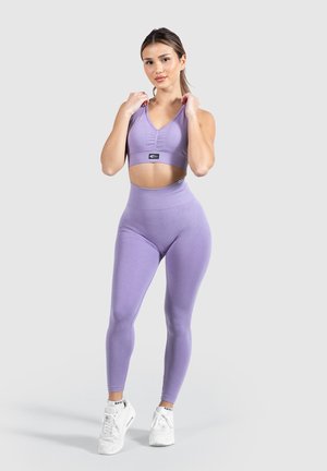 Hellblaues Workout-Set mit einem kurzen Sport-BH und V-Ausschnitt sowie hochtaillierten Leggings. Glatte Textur, figurbetontes Design.