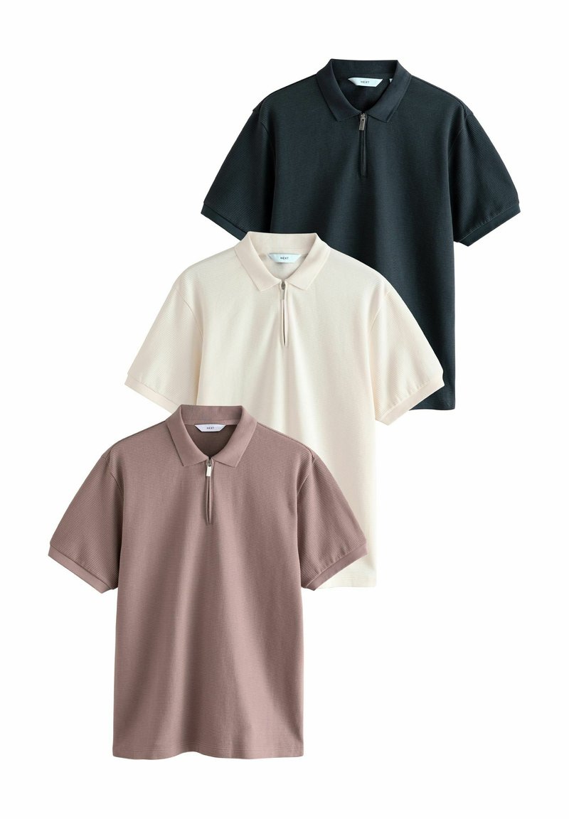 Tres camisetas polo en negro, crema y malva, con cuello de media cremallera, mangas cortas, textura acanalada y diseño de corte relajado.