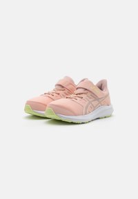 Baskets de sport roses avec une tige en maille, des fermetures à lacets et Velcro, une semelle intermédiaire blanche et des détails en vert sur la semelle extérieure.