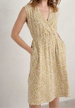 Floral-patterned sleeveless dress featuring a V-neck, cinched waist, and side pockets; colors include white with mustard yellow accents.