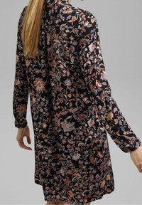 Svart blommig klänning med långa ärmar, prydd med livfulla orange, blå och vita blommönster. Mjuk tyg med en avslappnad passform.