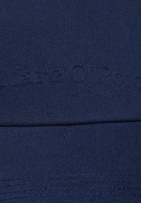 Casquette de baseball bleu marine en coton, avec un tissu texturé et une inscription en relief subtile sur le devant. Bords de visière lisses.