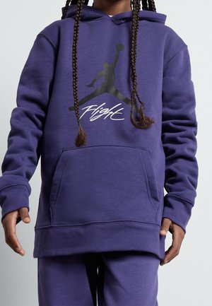 Person wearing a purple hoodie and matching pants with a black Jumpman silhouette and "Flight" text on the hoodie front.