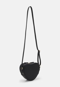 Czarna torebka typu crossbody w kształcie serca, wykonana z gładkiego materiału, z zamkiem błyskawicznym i regulowanym paskiem z akcentami w kolorze złotym.