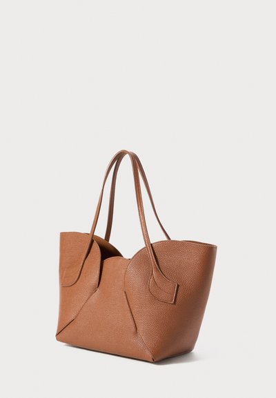 Braune, strukturierte Ledertasche mit abgerundeten oberen Kanten und zwei schlanken Schulterträgern auf einem weißen Hintergrund.