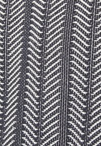 Tissu tricoté en noir et blanc avec des motifs en chevron vertical et des rayures en rangées alternées.
