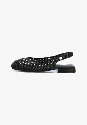 Zapato plano de tirante negro tejido con puntera redondeada, diseño de patrón abierto y un bajo tacón negro. Presenta una correa texturizada y un sutil acento de metal.