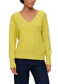 Geel V-hals trui van gestructureerd breiwerk, met lange mouwen en geribbelde manchetten en zoom. G gedragen met donkerblauwe jeans.
