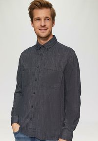 Donker herringbone-patroon overhemd met knoopsluiting, kraag, twee borstzakken en lange mouwen. Gemaakt van een gestructureerde stof.