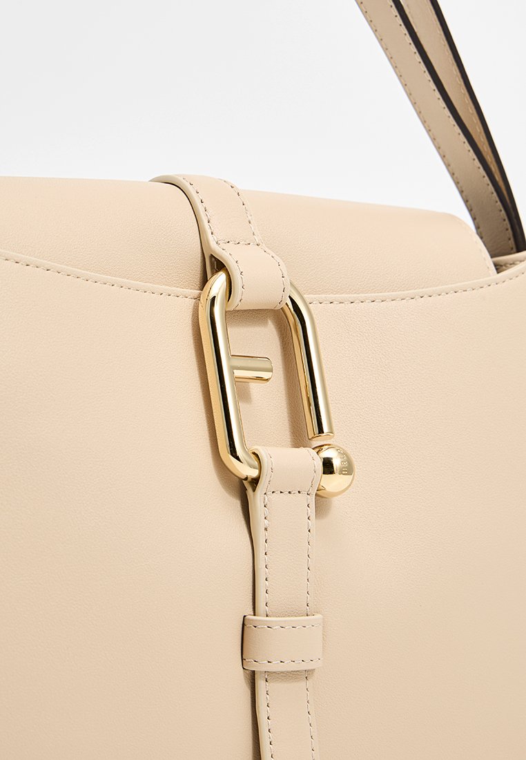 Borsa a tracolla in pelle beige con dettagli in metallo dorato. Presenta un design strutturato, una tracolla regolabile e un meccanismo di chiusura a scatto. Texture morbida.