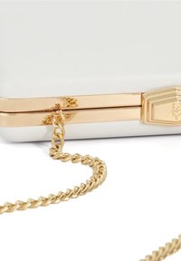Biała kopertówka z złotym łańcuszkiem. Posiada złoty zamek i akcenty, gładką fakturę oraz prostokątny kształt.