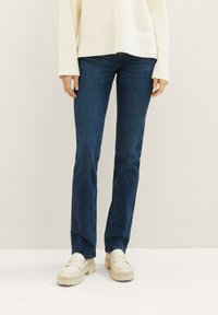 Mørkeblå denimjeans med rett passform, en myk tekstur og minimale sømdetaljer, kombinert med kraftige kremfargede loafers.