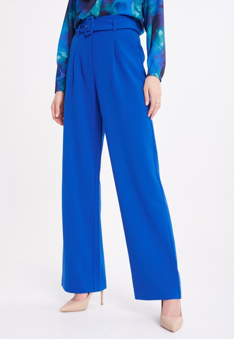 Pantalons larges bleu vif avec une taille haute et une ceinture assortie. Tissu lisse avec des plis pressés et une coupe ajustée.