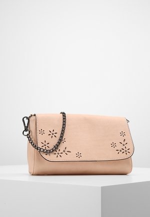 Beige Clutch mit floralen Ausschnitten und kleinen Strasssteinen, mit einem dunklen Kettenriemen auf einem weißen Podest.