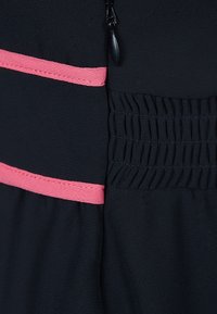 Robe en tissu noir avec des accents roses et un détail smocké sur le côté, soulignant la texture et le contraste du design.