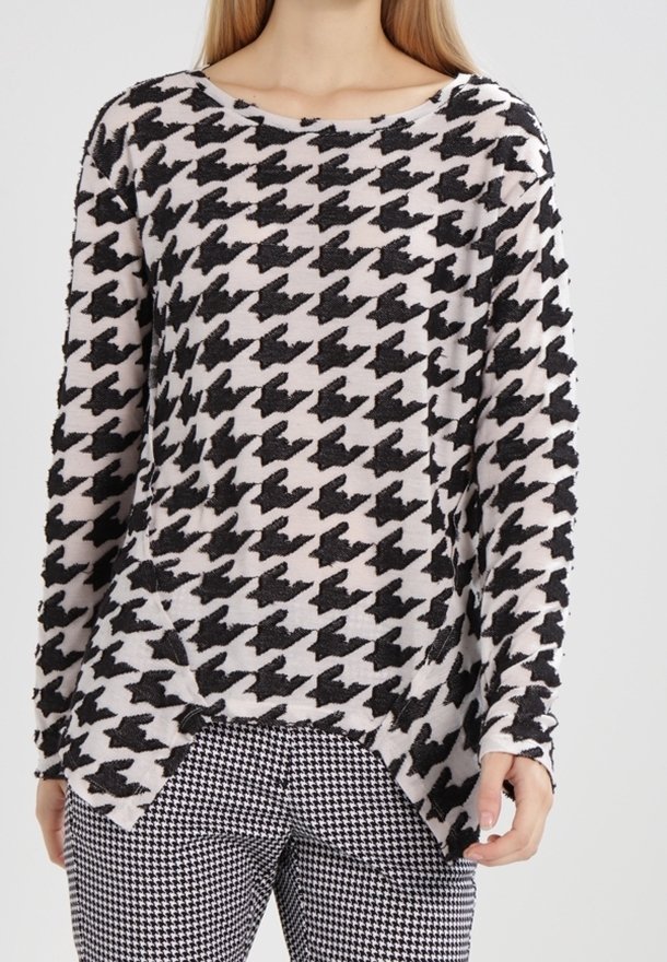 Pull à manches longues en tissu doux avec un motif pied-de-poule noir et crème, doté d'un col rond et d'une fente sur les côtés à l'ourlet.