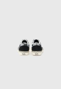 Black and white checkerboard canvas shoes with a suede heel, featuring a white rubber sole and signature logo on the back.