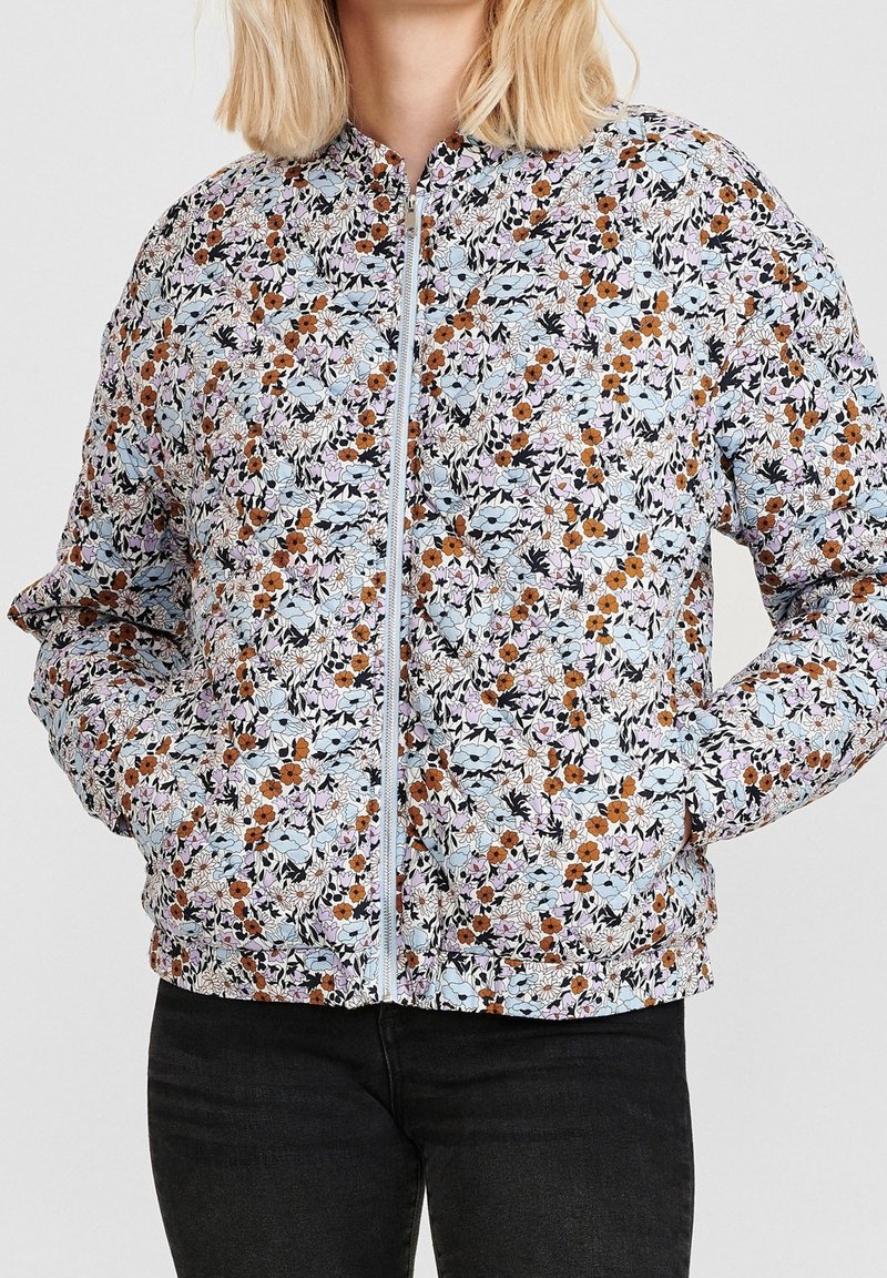 Květinová bomber bunda s světle modrým pozadím, smíchaným s oranžovými, bílými a růžovými květinami. Má přední zip a přiléhavé manžety.