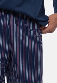 Pantaloni da pigiama navy con righe verticali in rosso e bianco; tessuto morbido; cintura elastica con cordino per una vestibilità regolabile.
