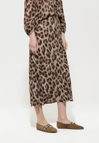 Braun und beige Leopardenmuster-Kleid mit einem Bindedetail am Ausschnitt, kombiniert mit hellbraunen Ballerinas mit dekorativen Schnallen.
