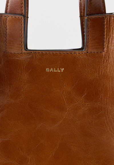 Καφέ δερμάτινη τσάντα χειρός με ορατές ραφές και χρυσό λογότυπο "BALLY" στο κέντρο κάτω από το άνοιγμα της χειρολαβής.