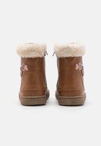 Braune Kunstleder-Stiefeletten mit weicher cremefarbener Fütterung, strukturierten Sohlen und zwei pinken Herzdetails an den Seiten.