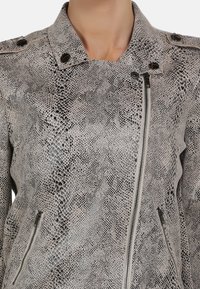 Veste en cuir à motif serpent de couleur gris clair avec un col, fermeture éclair à l'avant et deux poches latérales. Présente des accents métalliques et une surface texturée.